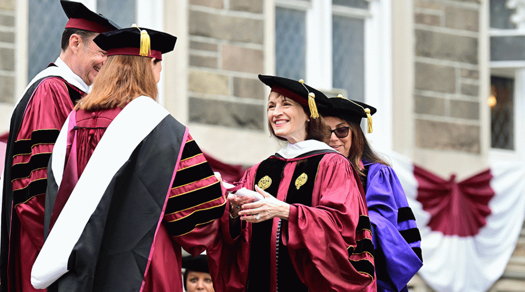 woman receives degree in maroon robe and grad cap