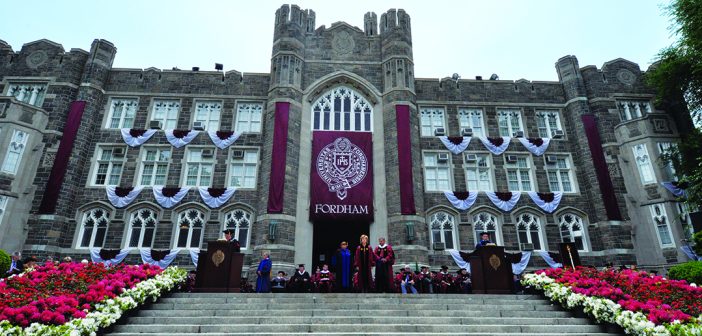 An upward photo of Keating Hall, the stairs are in the forefront. There are flowers on both sides of the stairs.