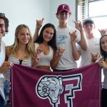 Six students hold a maroon banner.