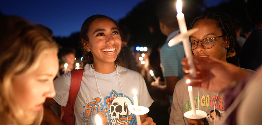 A girl smiles at a lit candle.