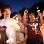 A group of men excitedly hold up lit candles.