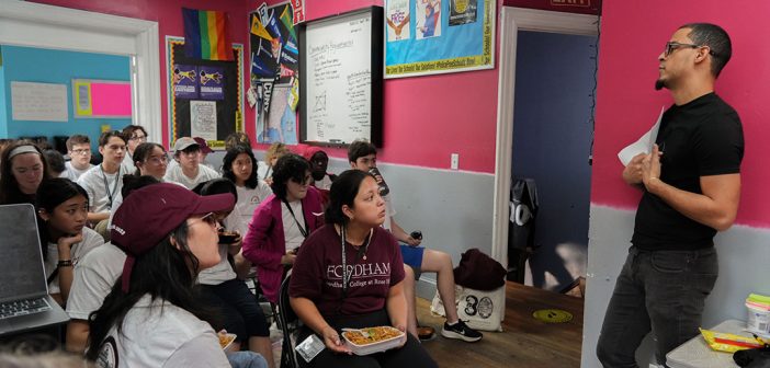 Students seated, listening to a presentation from a representative of the Northwest Bronx Community & Clergy Coalition.