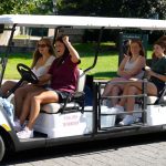 A girl drives a golf cart with passengers.