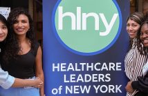 four women standing next to a banner that says Health Care Leaders of New York