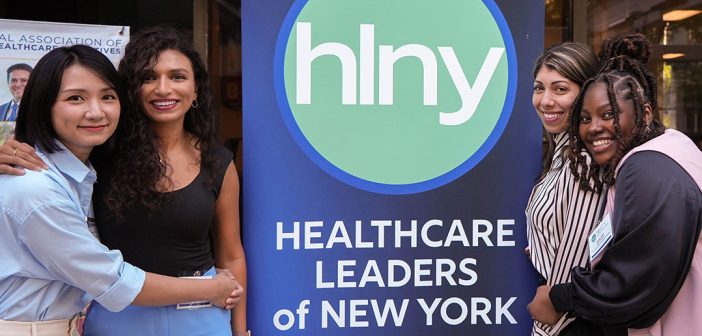 four women standing next to a banner that says Health Care Leaders of New York