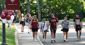 People wearing Fordham T-shirts and walking on the Rose Hill campus during Homecoming weekend in 2022