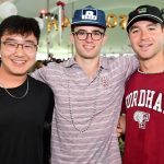 Three young students or alumni posing in Homecoming tent.