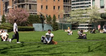 Students study in chairs and walk around the grassy plaza at the Lincoln Center campus.