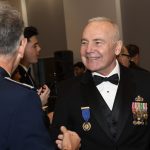 A man wearing military medals smiles at someone.