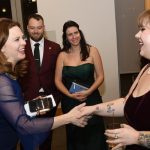 Tania Tetlow joyously shakes hands with someone while three onlookers smile.