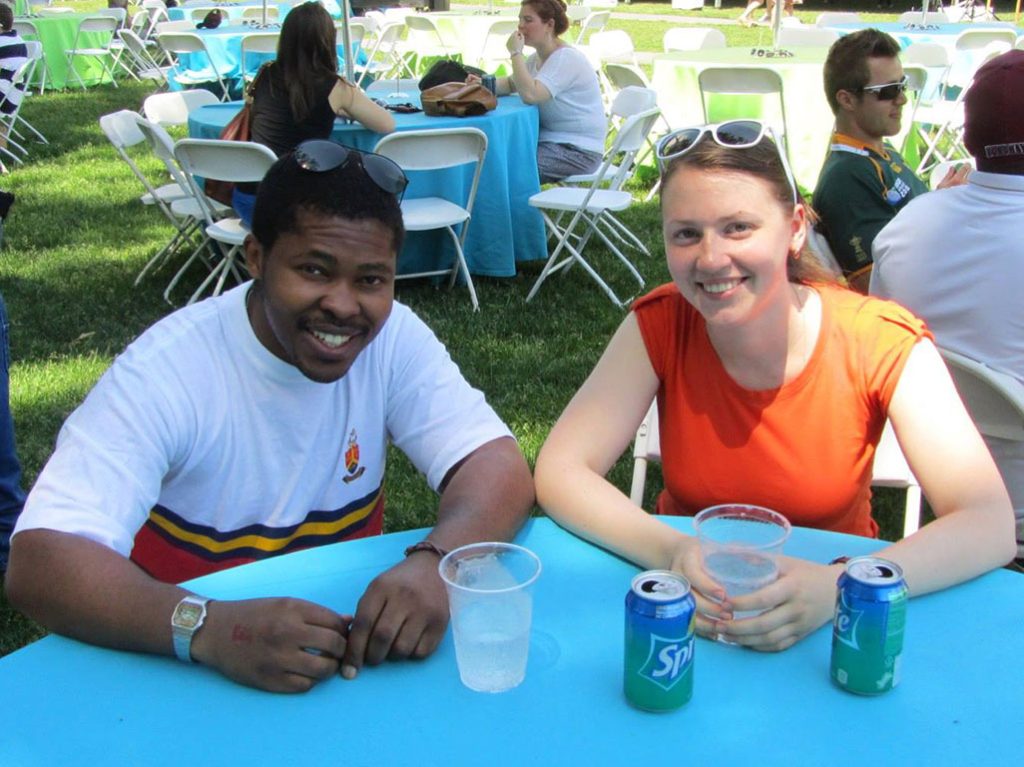 A man and a woman sitting at an outdoor table with drinks in front of them.