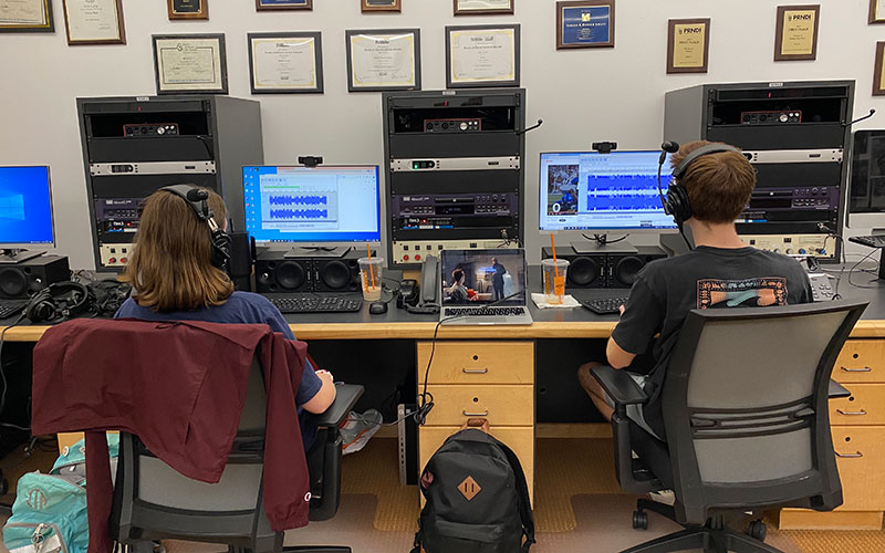 Estudiantes trabajando en computadoras en la sala de redacción.