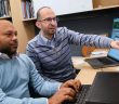 Ruhul Amin and Mohamed Rahouti sit and work at a computer.