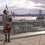a man plays the bagpipes on a porch